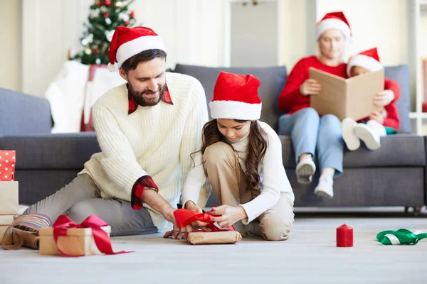 Little Santa Girl Tying Knot Top Packed Giftbox While Father — Stock Photo, Image