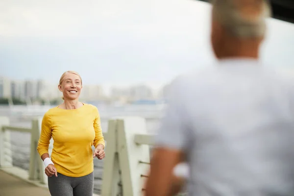 快乐的老年妇女微笑着向男子跑向她 而在城市环境中训练上午 — 图库照片