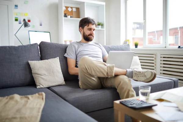 Jovem Homem Relaxado Sentado Sofá Com Laptop Frente Assistindo Webcast — Fotografia de Stock