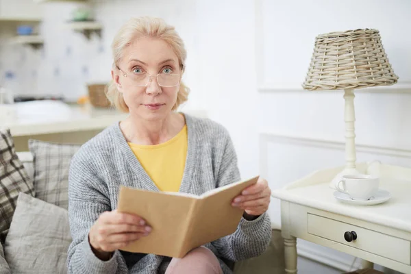 Leeftijd Ernstige Vrouw Bril Kijken Camera Terwijl Leesboek Gemak Thuis — Stockfoto