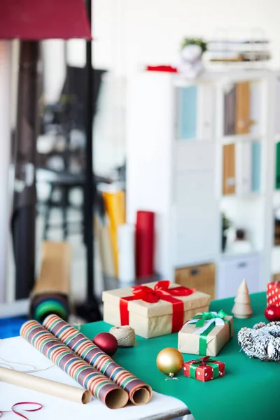 工作室的桌子 有圣诞装饰 卷包装纸和包装的礼物在礼品盒 — 图库照片