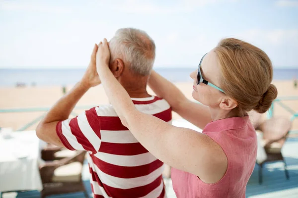 Flirty woman covering eyes of her husband while standing behind him during their vacation at summer resort