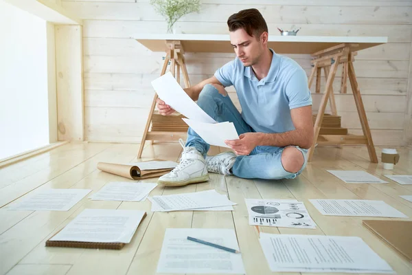 Young Serious Businessman Casualwear Sitting Floor Reading Papers Studio — Stock Photo, Image