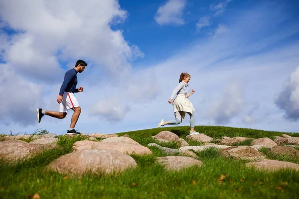 Active Guy Girl Running Large Stones Green Field Cloudy Sky — Stock Photo, Image