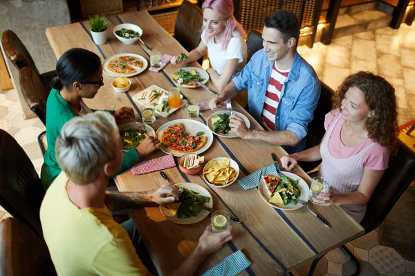 五个穿着休闲装的年轻人坐在木桌旁 在咖啡馆里聊天 享用健康的午餐 — 图库照片