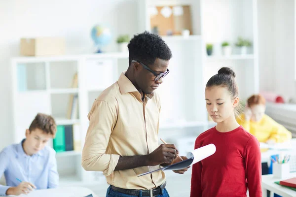 Ung Självsäker Lärare Förklarar Skolflicka Några Misstag Sin Uppsats Lektionen — Stockfoto