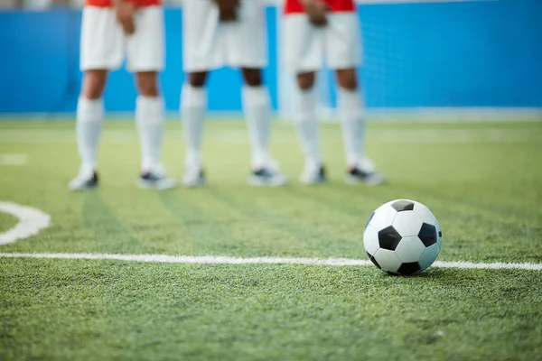 足球在绿色足球场由三个球员的分界线和腿在背景 — 图库照片