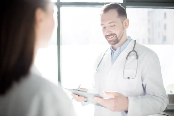 Jovem Médico Feliz Lendo Notas Médicas Enquanto Comunica Com Seu — Fotografia de Stock