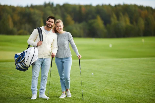 穿着休闲装站在大绿地上打高尔夫球的幸福年轻夫妇 — 图库照片