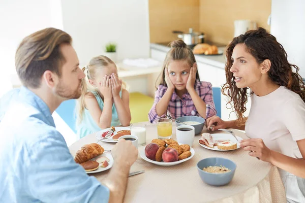 神経質な若い女性と彼女の夫は 近くに座って 彼らを見て 彼らの娘と朝食で対立している — ストック写真
