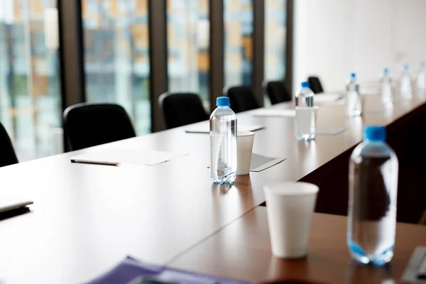 Närbild Trä Konferensbord Med Slutna Flaskor Vatten Glas Papper Och — Stockfoto