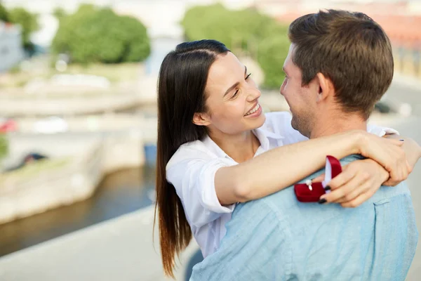 快乐的女孩拿着订婚戒指和拥抱她的男朋友 而看着他的眼睛 — 图库照片