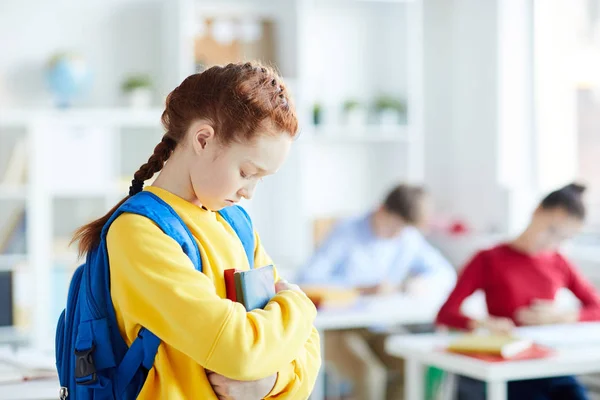 悲伤或冒犯女学生背包和书籍站在教室的同学 — 图库照片