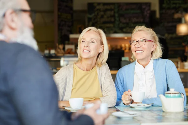 つはかなり陽気な女性がカフェで彼らの話の中に年配の男性をスマート カジュアルな見ることで高齢者 — ストック写真
