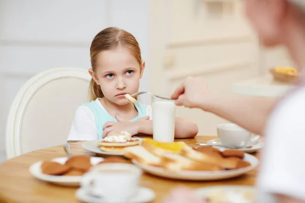 彼女の母親がフォークで彼女を養うときに食べることを拒否しながら 恨みを持って見て怒った怒った女の子 — ストック写真