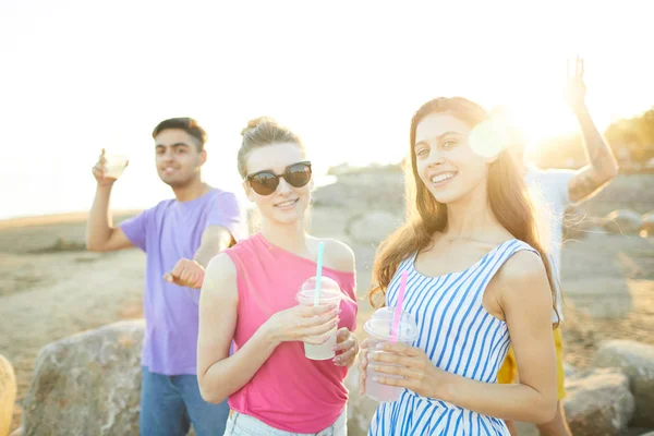 Duas Garotas Atraentes Com Bebidas Seus Namorados Dançando Fundo Praia — Fotografia de Stock