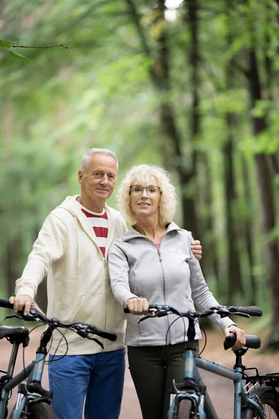 Retired couple in activewear spending summer weekend in park with bicycles