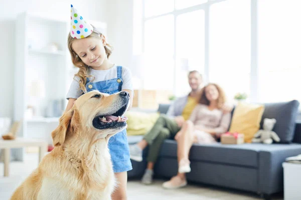 可爱的孩子在生日帽站在她的狗和拥抱他与放松的父母的背景 — 图库照片