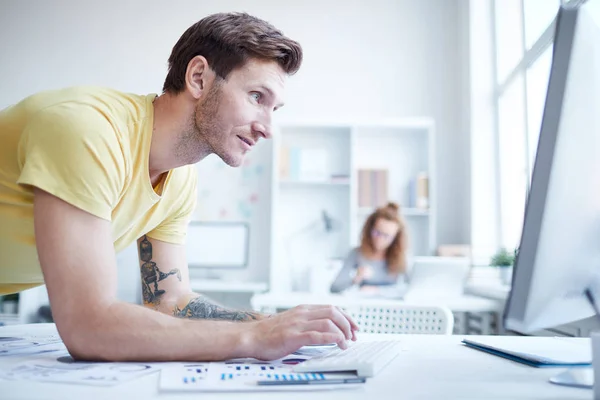 Joven Hombre Negocios Casual Mirando Pantalla Computadora Mientras Inclina Sobre — Foto de Stock