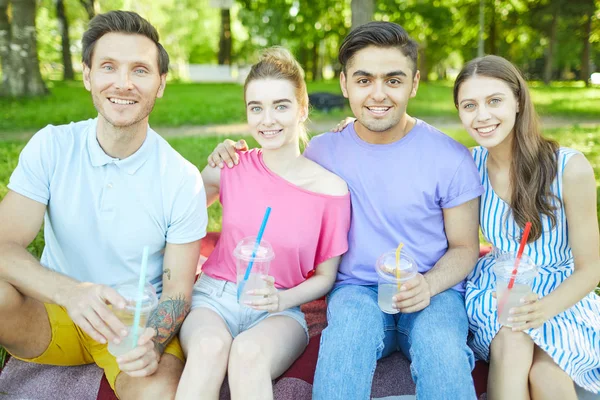 夏の日に自然環境で休息を楽しむ飲み物を持つ2人の若い愛情のカップル — ストック写真