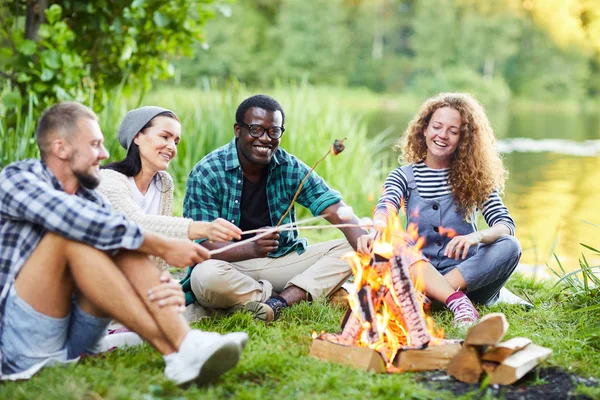 Young Cheerful Campers Sitting Campfire Making Marshmellows Enjoying Evening Waterside — Stock Photo, Image