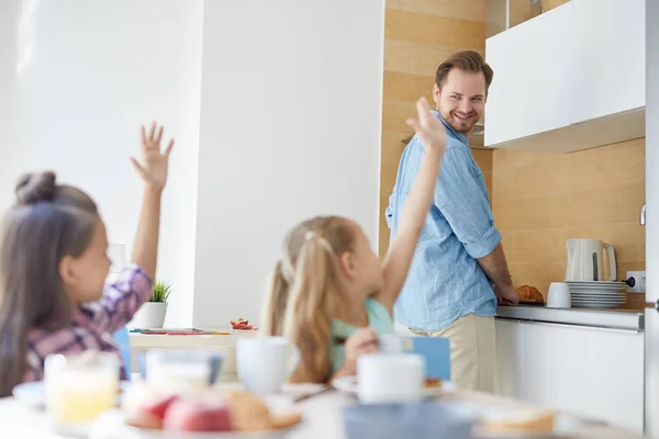 Jovem Olhando Para Suas Filhas Levantando Mãos Enquanto Cozinha Algo — Fotografia de Stock