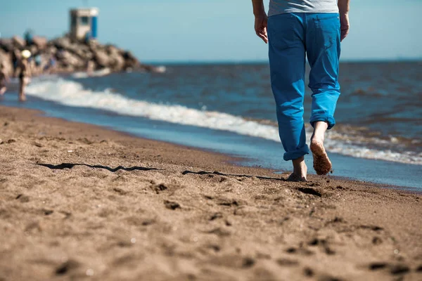 Kıyı şeridinde ıslak kum üzerinde hareket yalınayak adam düşük bölümünün arkadan görünüm