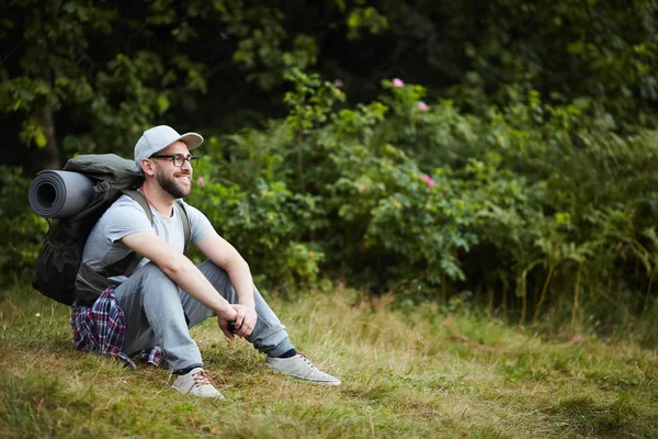 Ung Resenär Med Ryggsäck Sitter Gräset Och Vilar Och Tittar — Stockfoto