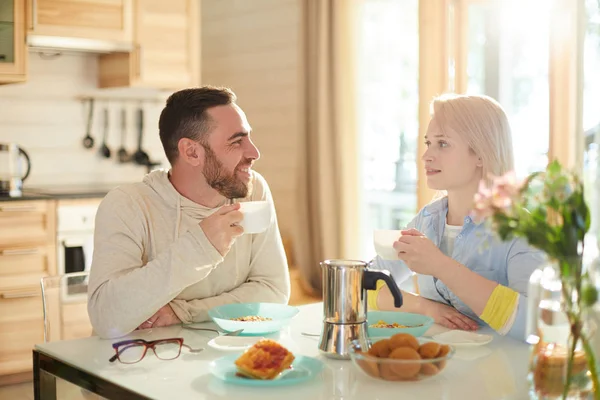 年轻的已婚白种人夫妇坐在舒适的厨房里的桌子上 喝咖啡 吃早餐 谈论周末的计划 — 图库照片