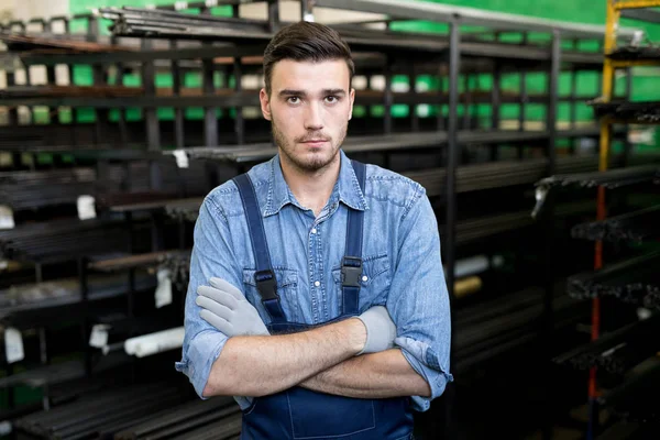 鋼鉄の生産のために工場で腕を組んで全体的に立っている若い労働者の肖像画 — ストック写真