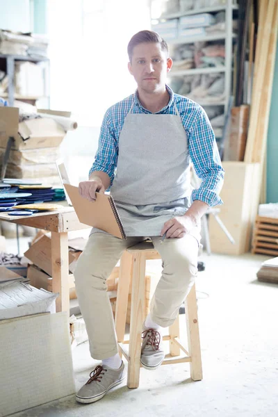 Νεαρός Δημιουργικός Άνδρας Ενδύματα Εργασίας Κάθεται Καρέκλα Στο Εργαστήριό Του — Φωτογραφία Αρχείου