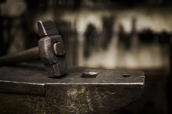 暗い鍛冶場で耐久性のあるスチールアンビルに置かれた重いハンマーのクローズアップ — ストック写真