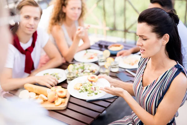 Portrait of frustrated woman complaining about food during lunch with friends in cafe, copy space