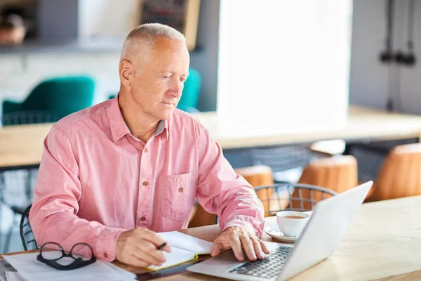 Poważnego Wieku Biznesmen Różowej Koszuli Siedzi Przy Stole Przed Laptop — Zdjęcie stockowe