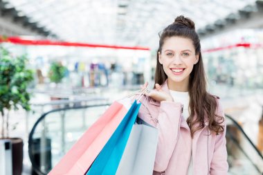 Sana bakmak ve paperbags tutarak dişlek gülümseme ile genç ve güzel alışveriş