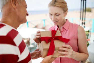 Mutlu yaşlı kadın onun Doğum günü veya yıldönümü için kocası tarafından verilen giftbox göz alarak