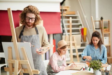 Arka planda çizim iki kız ile şelon üzerinde palet ve paintbrush boyama ile ciddi adam