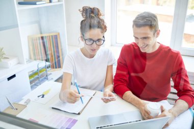İki genç yaratıcı tasarımcı yan yana masa başında oturuyor ve yeni fikirleri tartışıyor
