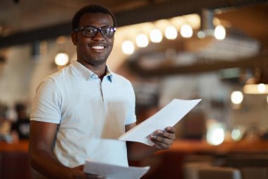 Genç ve başarılı bir işadamı çalışma sırasında modern kafede size bakıyor.