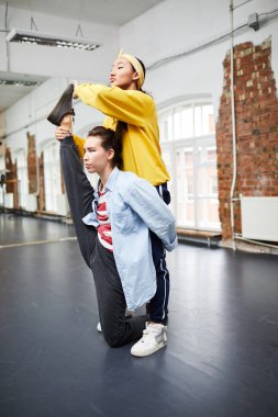 Aktif kızlardan biri, grup arkadaşı veya eğitmen egzersiz sırasında ona yardım ederken bacak germe
