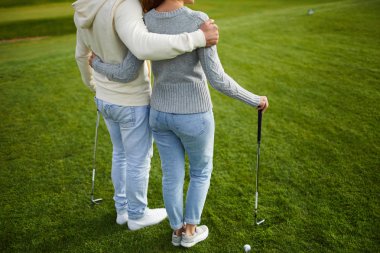 Oyundan önce yeşil çim üzerinde duran kulüpleri ile iki genç Casual Golf oyuncuları