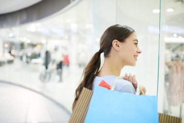 Vitrin tarafından ayakta ve yeni moda koleksiyonu bölümlerin birinde bakarak torba ile güzel müşteri