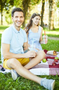 Kız arkadaşı ile piknik sırasında kameraya bakarak içki ile Mutlu genç adam