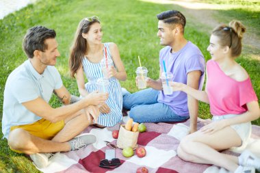Parkta sıcak yaz gününde piknik keyfi içecekler ile Mutlu genç arkadaşlar