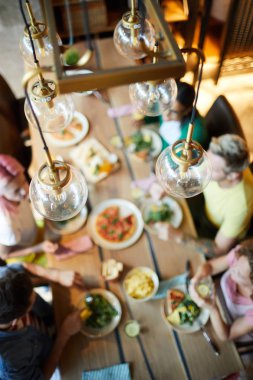 Birkaç cam küre lambalar etrafında oturan bir grup insan ile servis masa üzerinde asılı