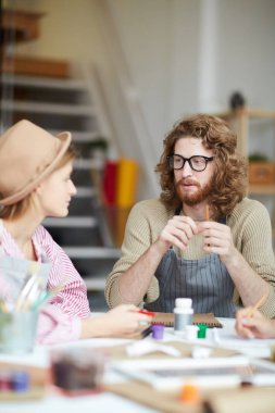 Genç adam ve grup arkadaşları masa başında oturup yeni yaratıcı proje hakkında konuşuyorlar.