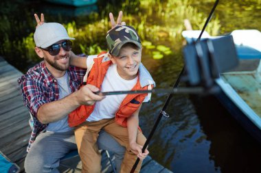 Baba ve oğlu balık avı sırasında selfie portresi yaparken akıllı telefonda kameraya poz