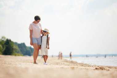 Yaz tatili sırasında plaj boyunca yürüyüş yaparken sevgi dolu modern anne sevgi dolu modern anne tam uzunlukta portre, kopya alanı