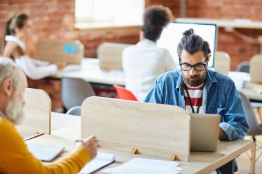 Çalışma ortamında işyeri tarafından net tarama casualwear ve gözlük sakallı işadamı