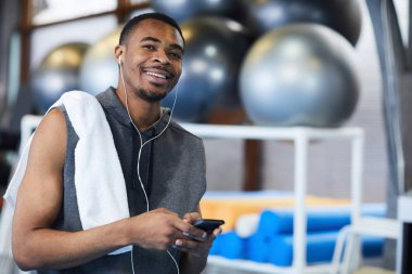 Müzik çalma listesindeki smartphone kopma egzersiz yaptıktan sonra seçim havlu ile mutlu genç sporcu